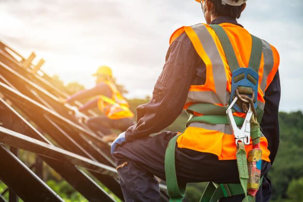 Experienced roofer using a safety harness while installing a roof.